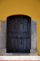 Old door in colonial city with yellow wall- Antigua Guatemala