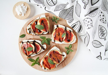Fig sandwiches on a wooden plate. Healthy sweet desserts. Fresh figs with mozzarella, chocolate and mint.