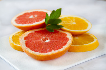 Fototapeta na wymiar Fresh grapefruit and orange are sliced on a white plate. Healthy food background. Food for weight loss