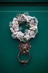 christmas wreath above lion door knocker on green door