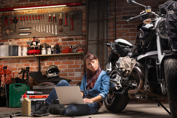 Fototapeta na wymiar Female mechanic checking for motorbike parts