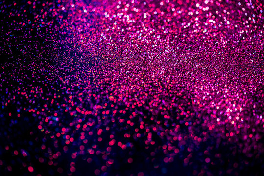 Pink/blue shiny glitter on black background. Macro shot, shalow DOF.