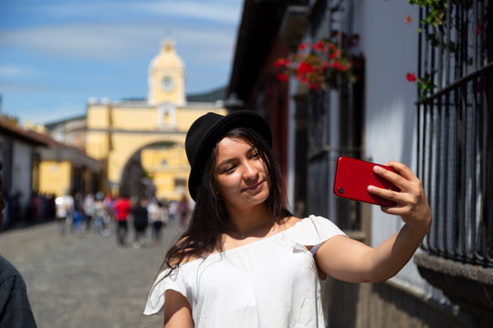 Young Hispanic woman taking a self in the city of Antigua Guatemala with the Santa Catalina arch behind