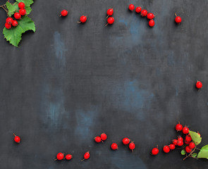 Christmas or Valentine's Day background with red sweet hawthorn berries on a black background.