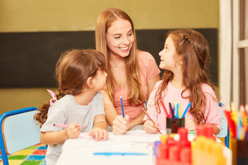 Kindergärtnerin und zwei Mädchen im Malkurs