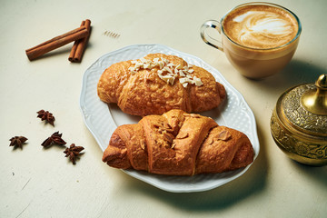 Two tasty croissants on a white plate on a white background. French croissant with nuts and coconut. Snack for breakfast. Close up. Food photography