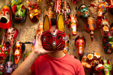 Young Hispanic man with a traditional handmade mask from Guatemala - Antigua Guatemala traditional...