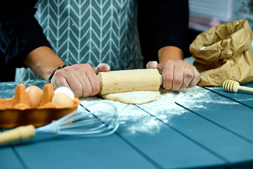 Obraz na płótnie Canvas Baker hands preparing fresh dough with rolling pin on kitchen table. Man forming the dough on a floured surface. Cooking pasta, spaghetti, pizza food concept.