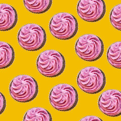 Seamless pattern of cupcakes with pink cream on a yellow background. The concept of a holiday, party, sweets, unhealthy food. Top view, flat lay, minimalism.