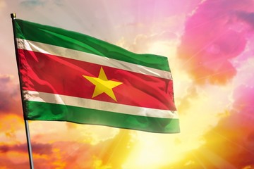 Fluttering Suriname flag on beautiful colorful sunset or sunrise background. Success concept.