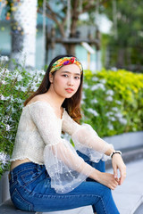 Portrait of beautiful sexy Asian woman sitting on step in the garden