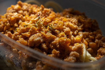 Pasta with minced meat and onion in navy-style on a gray background.