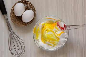 Making yellow colored whipped egg whites in glass bowl. top view