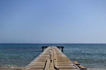 Symmetrical geometric photo. The old wooden sea pier and perfectly smooth calm sea