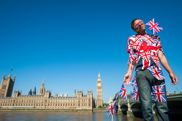 Confused European immigrant tangled in British Union Jack flag bunting standing in front of the city skyline at Westminster, London, UK - obrazy, fototapety, plakaty