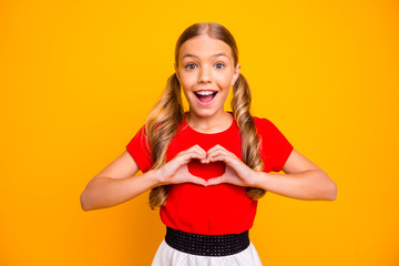 Photo of pretty small lady long tails hairstyle holding hands in heart figure excited good mood wear casual red white dress isolated bright yellow color background