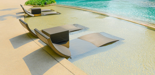 Beach chairs in luxury swimming pool.