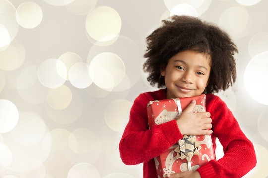 Christmas concept. Happy adorable african american child girl with christmas gift in hands isolated on white background.