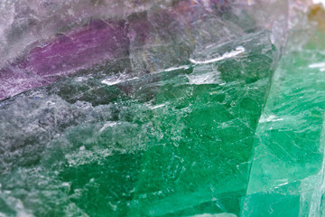 Close up detail on the surface of a green magenta and translucid fluorite mineral stone crystal isolated on white limbo background