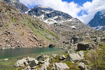 Fototapeta na wymiar The Green Lakes are little alpine lakes near Balme, Turin, Piedmont, Italy, in the Graian Alps, featuring turquoise clear water, surrounded by high mountains, meadows and rocks