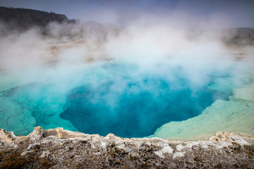 Blue geyser basin with boiling water from geothermal heat.