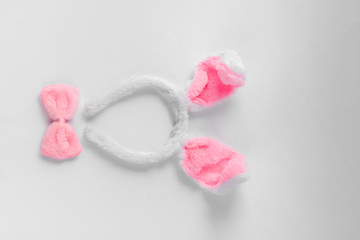Top view of cute bunny ears with a small pink bow on wooden background.