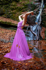 Fototapeta premium Portrait of a beautiful hispanic young woman near waterfall in autumn season