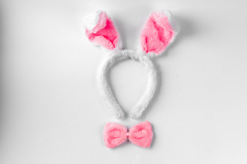 Obraz na płótnie Canvas Top view of cute bunny ears with a small pink bow on wooden background.