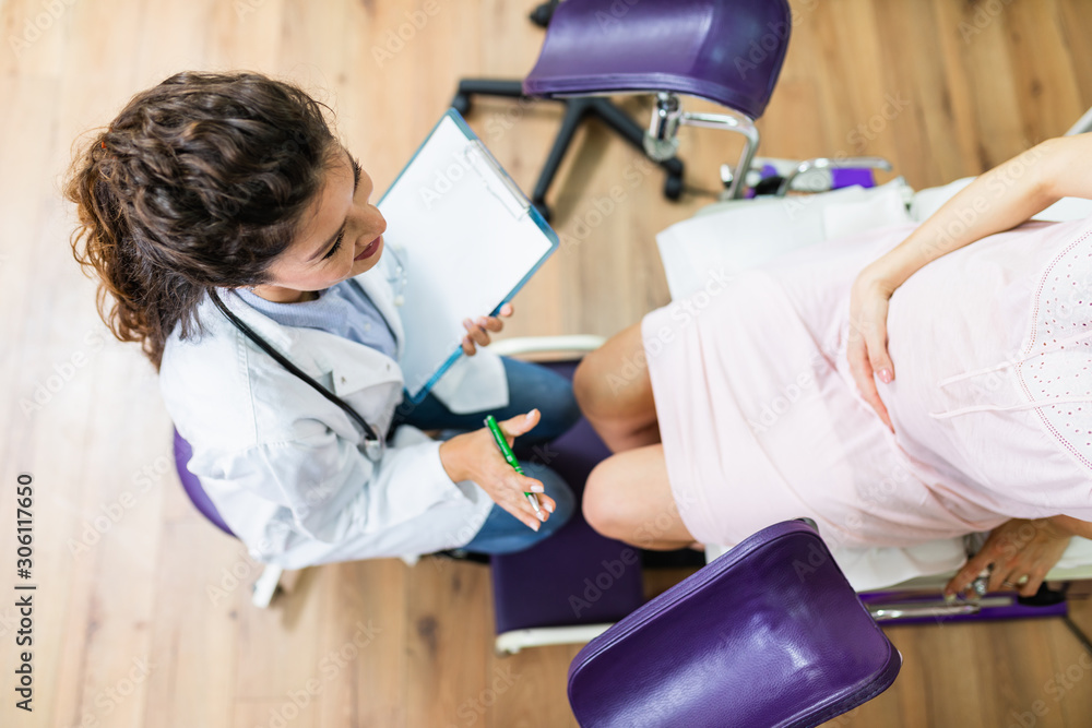 Wall mural Beautiful young pregnant woman in gynecological chair during gynecological exam.