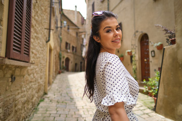 beautiful woman in summer dress walking and running joyful and cheerful smiling in Tuscany, Italy.