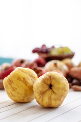 Quinces close up with a fall fruits  over a white wooden background .