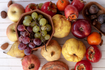Top view to fall fruits over a white wooden background.