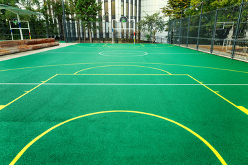 Empty landscaped children’s basketball court with green filling.