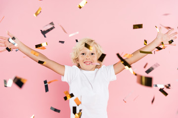 smiling kid with outstretched hands near falling confetti on pink background