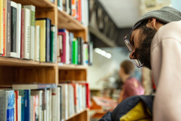 A young man selects a book on a shelf in a store. Education and hobbies. Close-up.