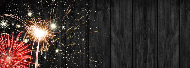 Festive silvester background banner panorama - Firework on a rustic black wooden texture, with space for text