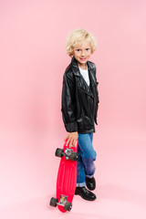 smiling and cute kid holding penny board on pink background