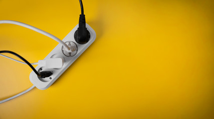 electricity consumption - electric extension cord full of power plugs on yellow background with...