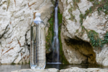 Big fresh water bottle on the background of the waterfall. Spring Water Images