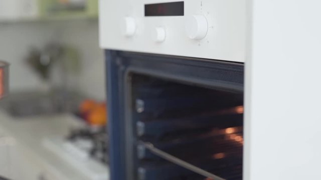 Close-up scene of a female cook who has just made a cheesecake and now has put it in an oven.