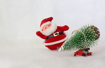 Toy car carrying Christmas tree in a snowy landscape on blurry Santa Claus background. Space for text.