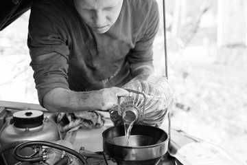 The concept of disability of people and their adaptation to life.A disabled person pours engine oil into the engine.There are no fingers on his hands.Disabled from childhood. Monochrome. Close up