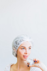 A young girl with well-groomed skin in a hat is holding a jar of cream in her hands. Place for text. Personal care.