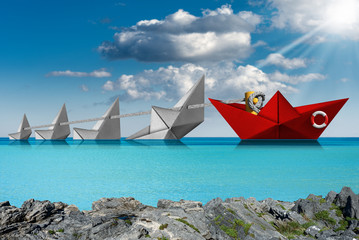Rescue and Leadership concept - Red and white paper boats in the sea