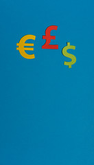 Paper yellow symbols of euro, dollar and pound currency on blue background. View from above with copy space.