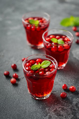 Refreshing cocktail with cranberry and mint on dark concrete background.