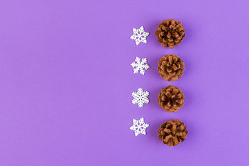 Top view of holiday composition made of pine cones and white snowflakes on colorful background. Winter time and Christmas concept with copy space