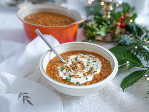 Red Lentil Dahl In A Bowl On A Festive Christmas  Table, With Natural, Green Table Runner And Napkin