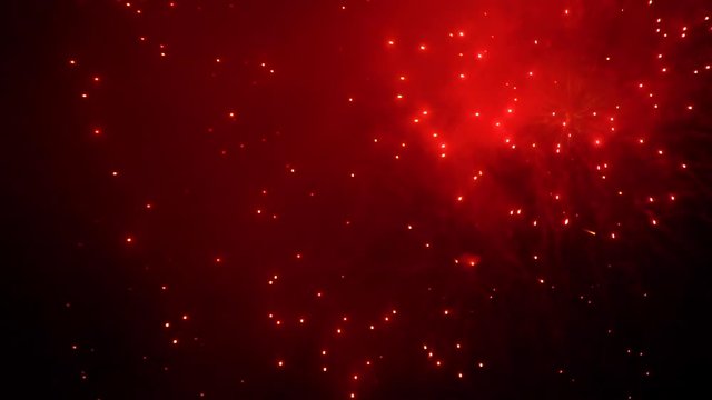 Beautiful Red Colored Sparks from Fireworks in the Night Sky in Slow Motion. The Concepts of Festivals, Holidays and City Celebrations