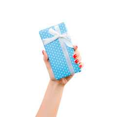 Woman hands give wrapped Christmas or other holiday handmade present in blue paper with white ribbon. Isolated on white background, top view. thanksgiving Gift box concept